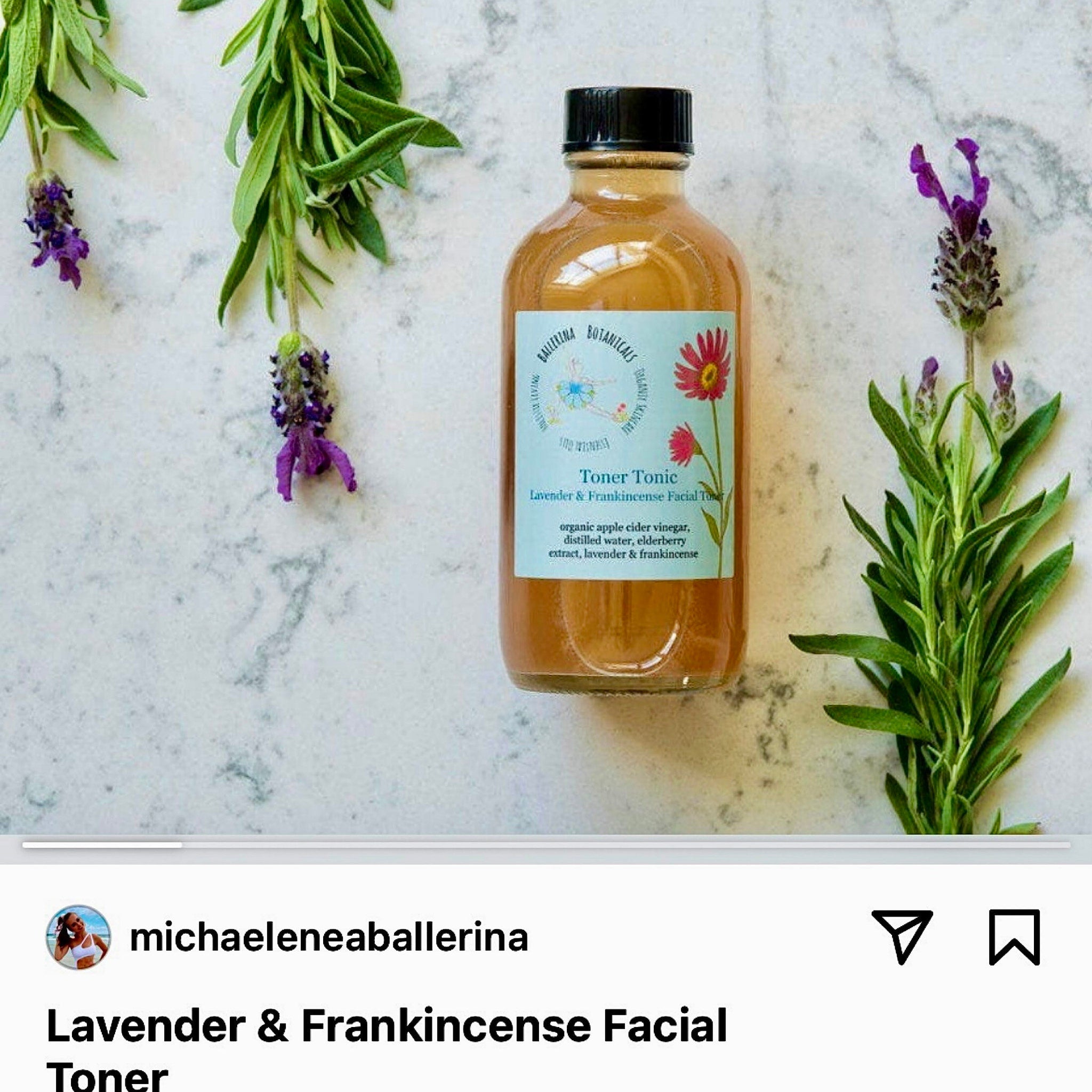 Facial toner bottle with label, amber liquid, black cap, and lavender sprigs on marble surface