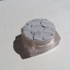 Close-up of pale matte gray mineral eyeshadow powder with soft, finely-milled texture in eco-friendly packaging