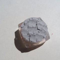 Side view of pale matte gray mineral eyeshadow in eco-friendly loose powder form with vegan label visible