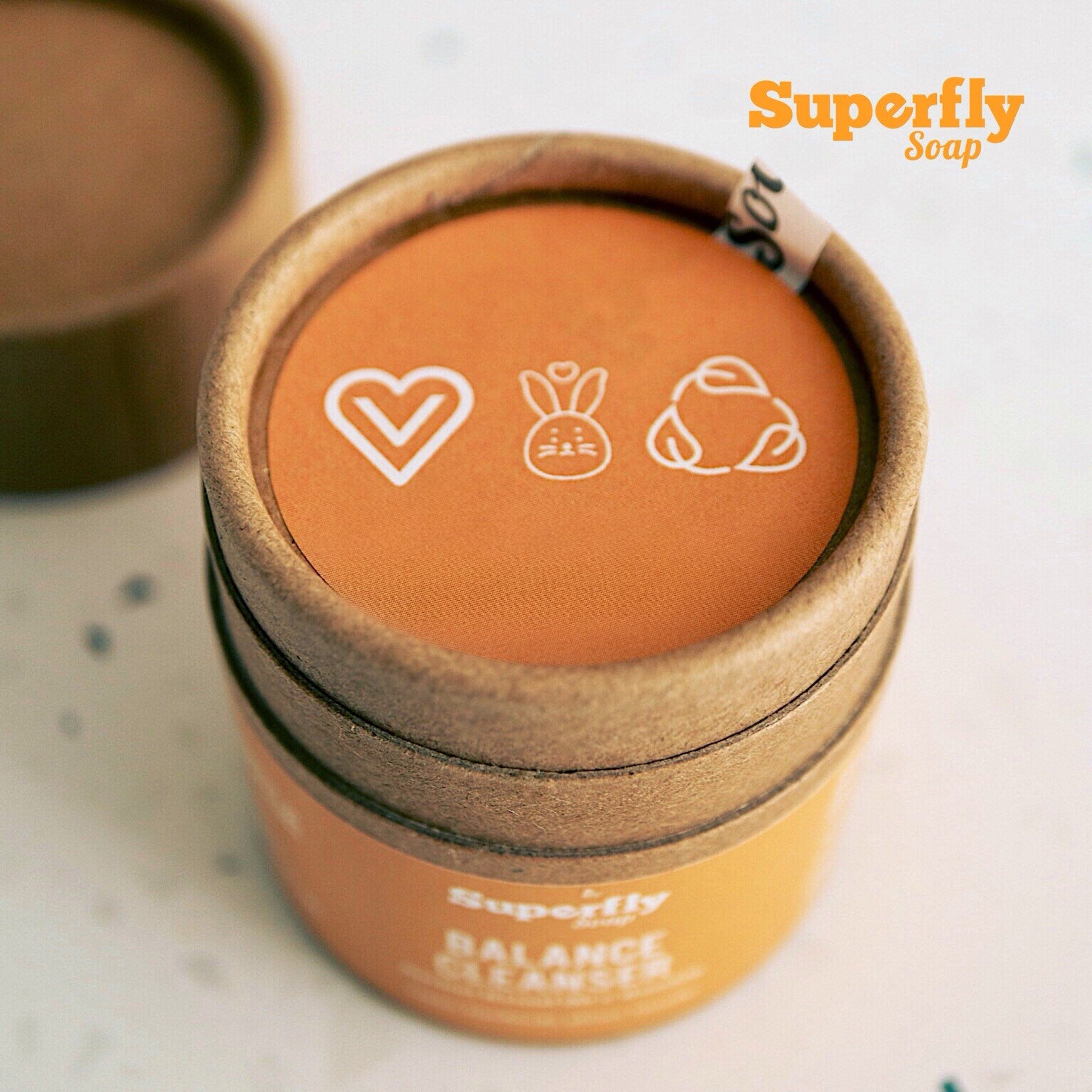 Soap container, orange and brown cardboard, Superfly branding, with white icons and text