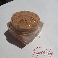 Side view of golden brown loose powder eyeshadow shimmering in sunlight with vegan cruelty-free label visible