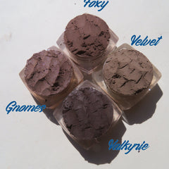 Four matte brown vegan loose mineral eyeshadows in round jars with black lids, arranged neatly on a white surface.