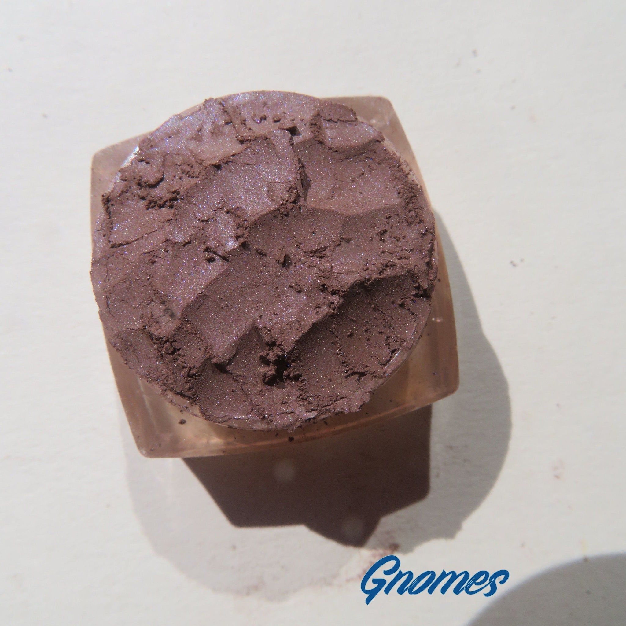 Side view of four matte brown loose mineral eyeshadows in round jars with black lids, showcasing texture and vegan labeling