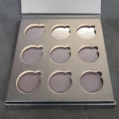 Close-up of matte black eyeshadow palette showing nine smooth, pigmented square pans in magnetic case