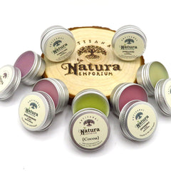 Lip balm tins with Natura Emporium labels, silver metal, various colors, on wood slice