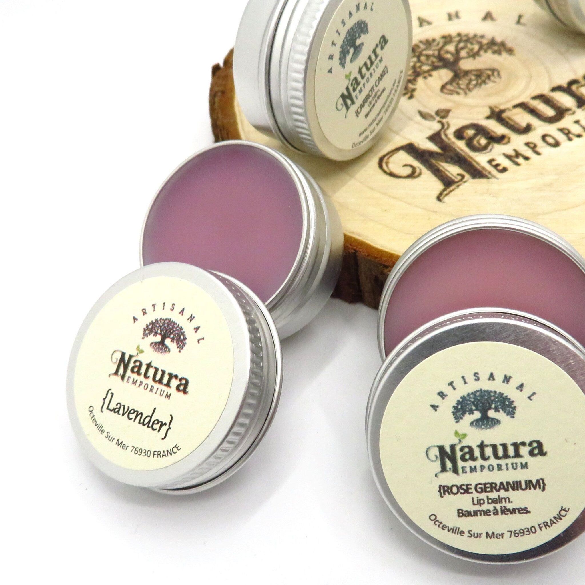 Lip balm tins with silver metal casing and Natura Emporium label, purple balm visible