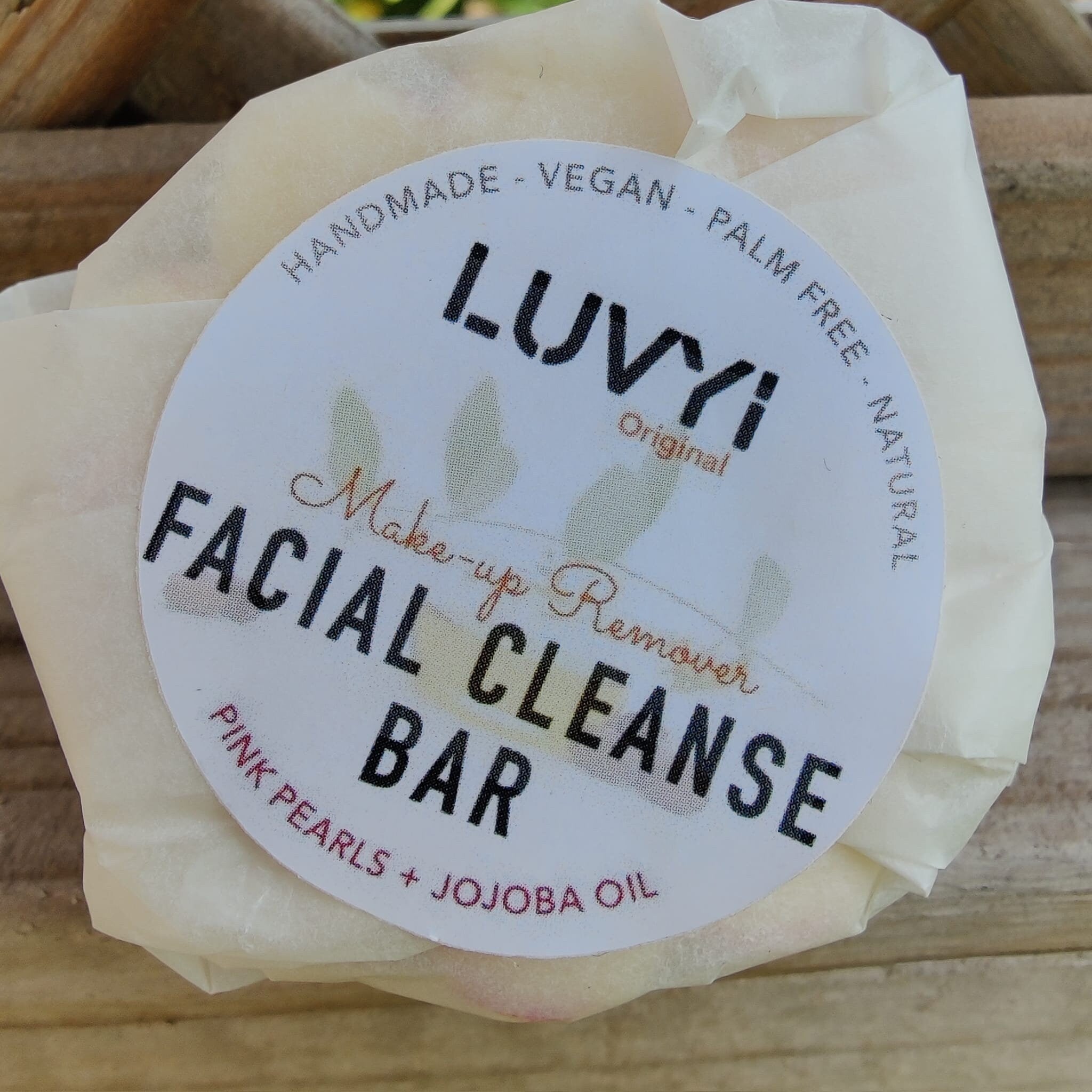 Facial cleanse bar wrapped in white paper with LUVVI label, pink accents, natural ingredients