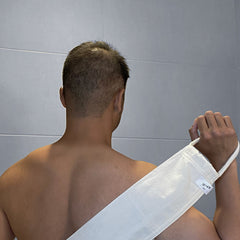 Back scrubber, white textured material, held by a person, with SENDE brand label visible