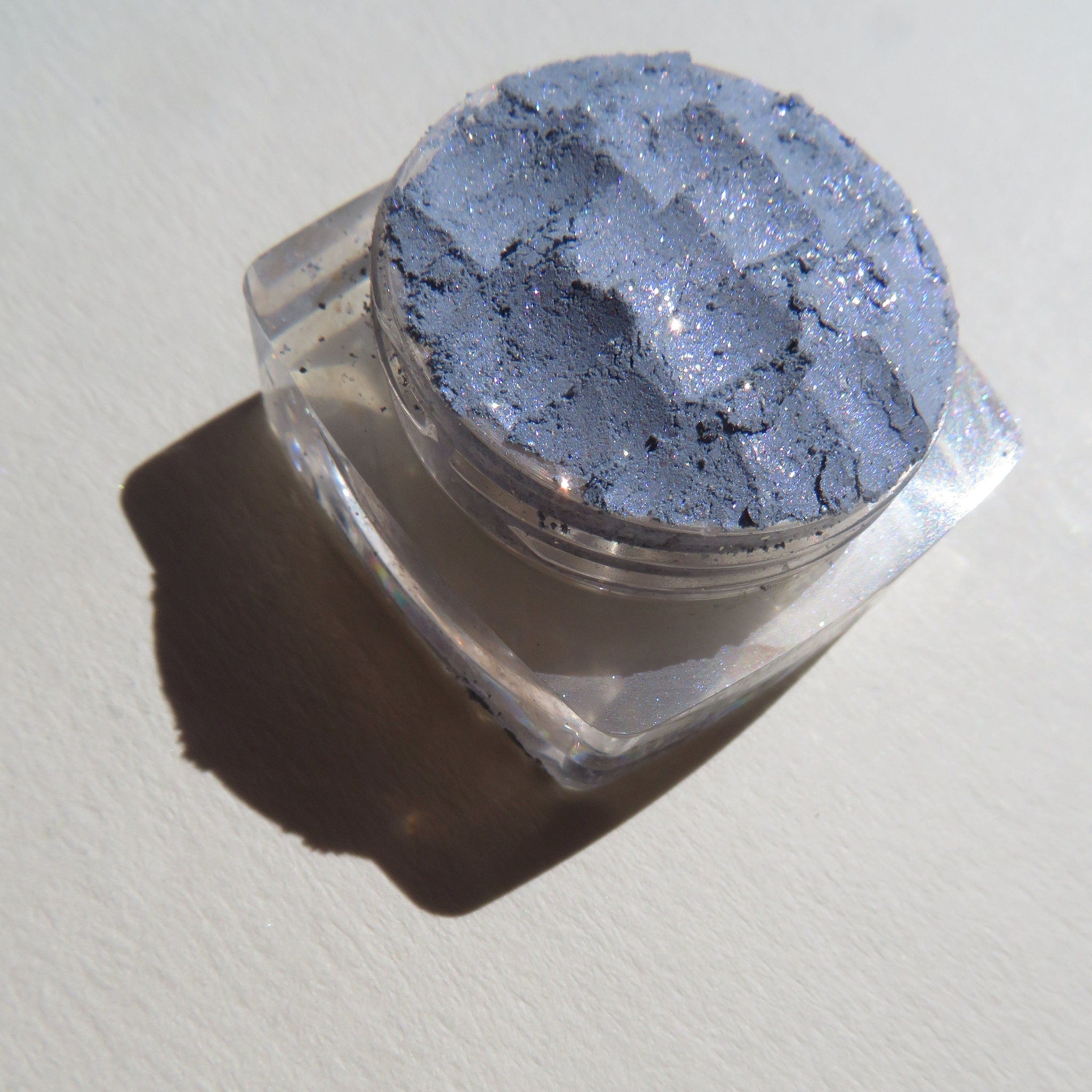 Open jar of Galactic Blue Gray loose mineral eyeshadow with shimmering sparkles, vegan and cruelty-free.
