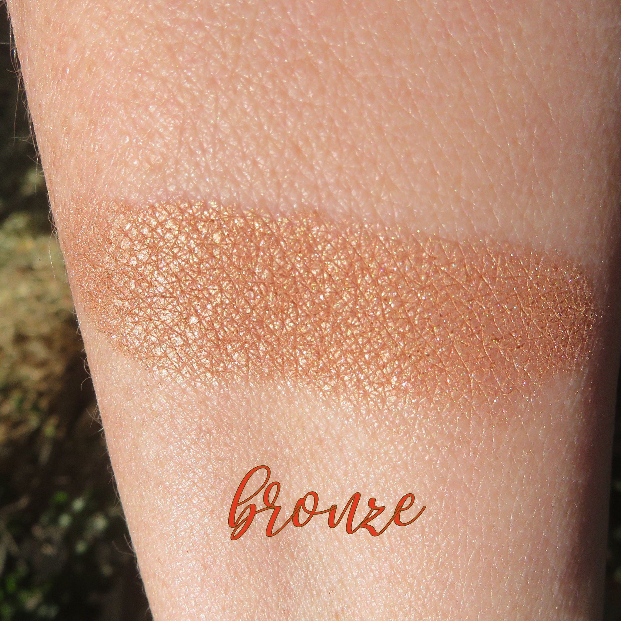 Side view of loose mineral eyeshadow in bronze copper brown shimmer, showcasing fine powder texture in jar