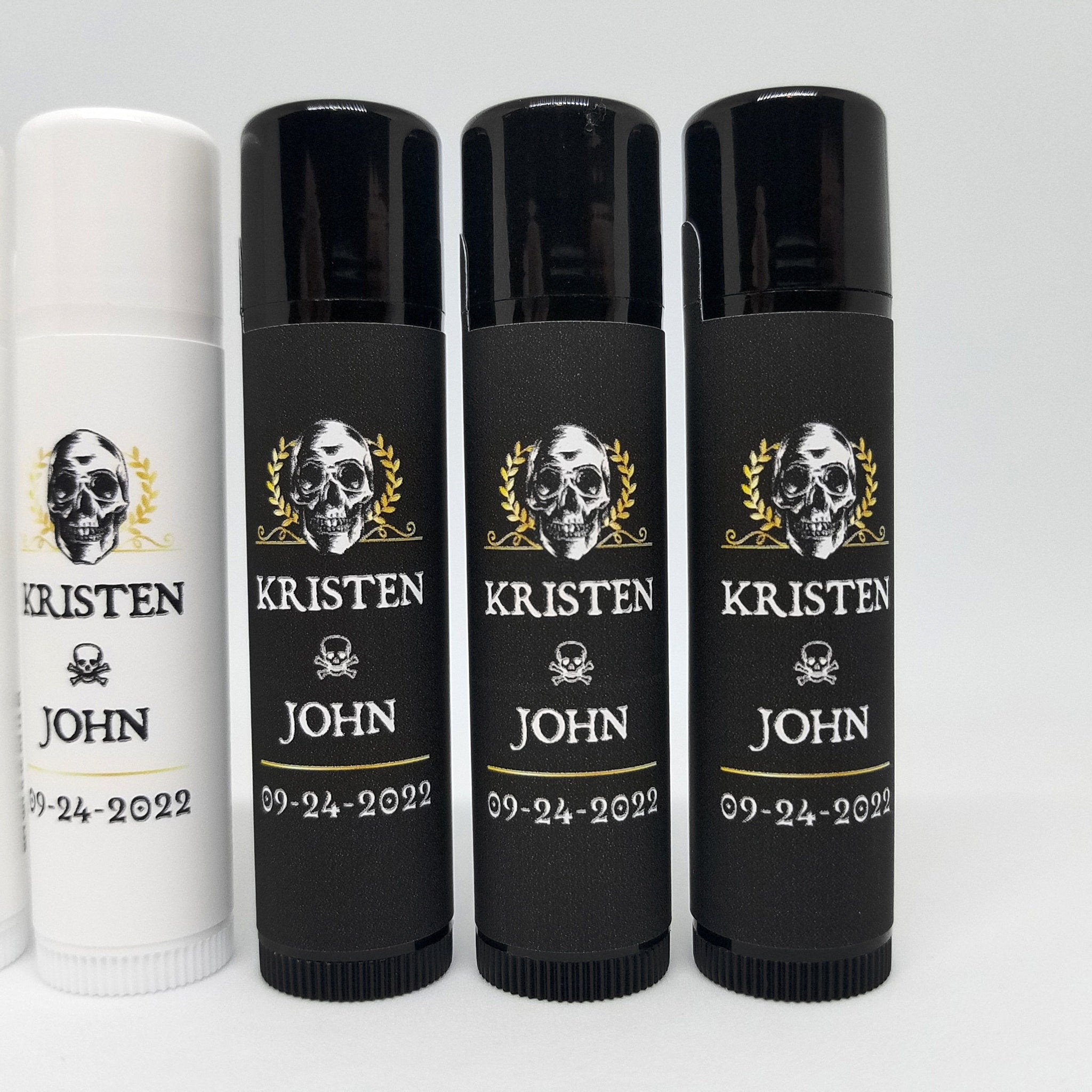 Lip balm tubes with black and white labels, skull design, and text reading "KRISTEN JOHN