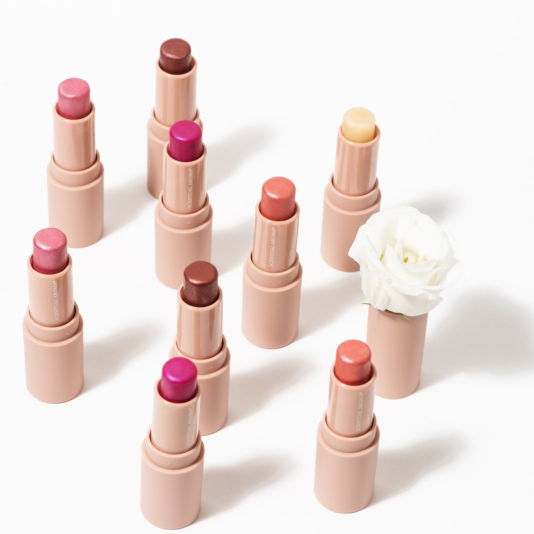 Lipsticks with pink, brown, and peach colors in beige tubes, Scentual Aroma branding visible