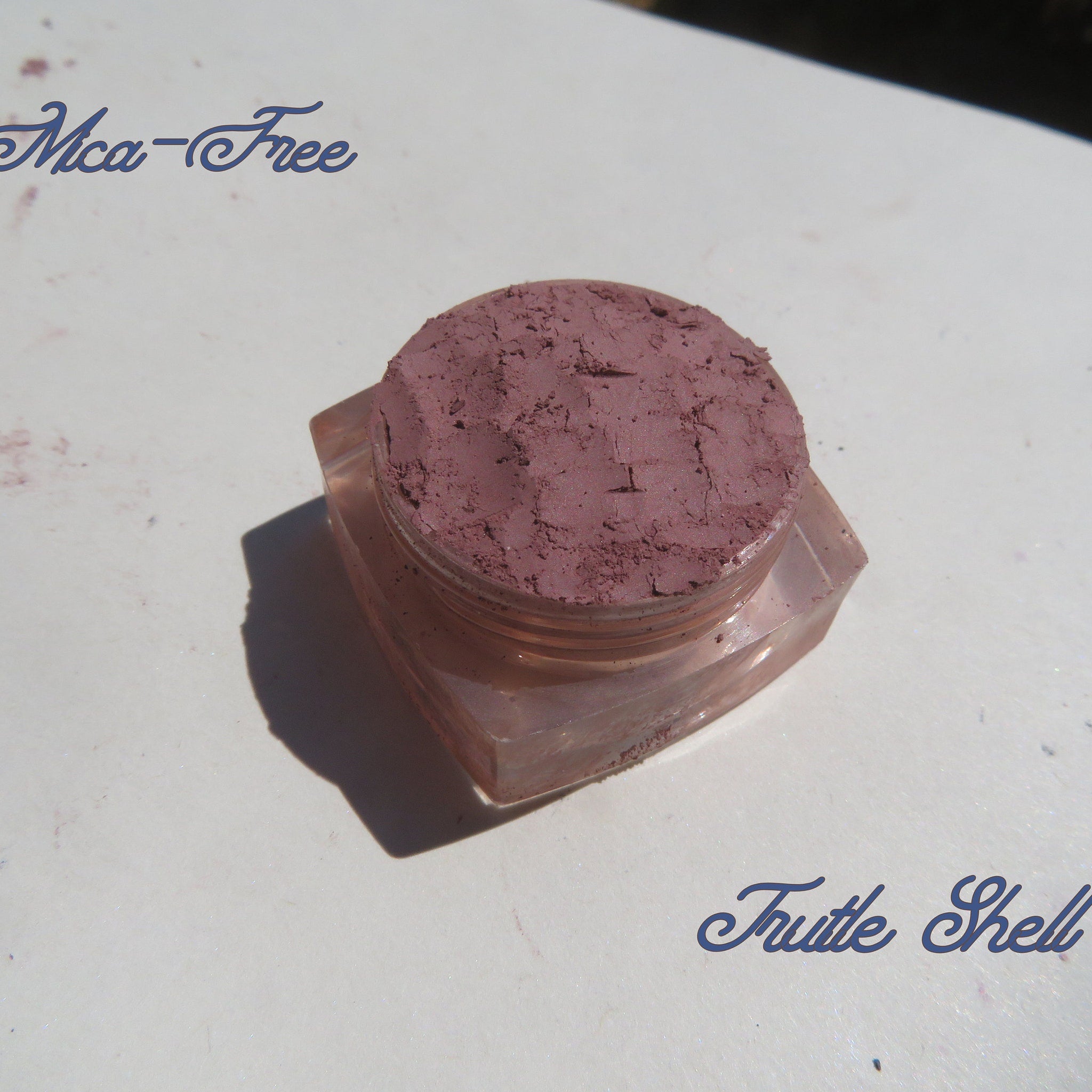 Side view of three matte loose mineral eyeshadows in glass jars showing vegan pigments from a diagonal angle