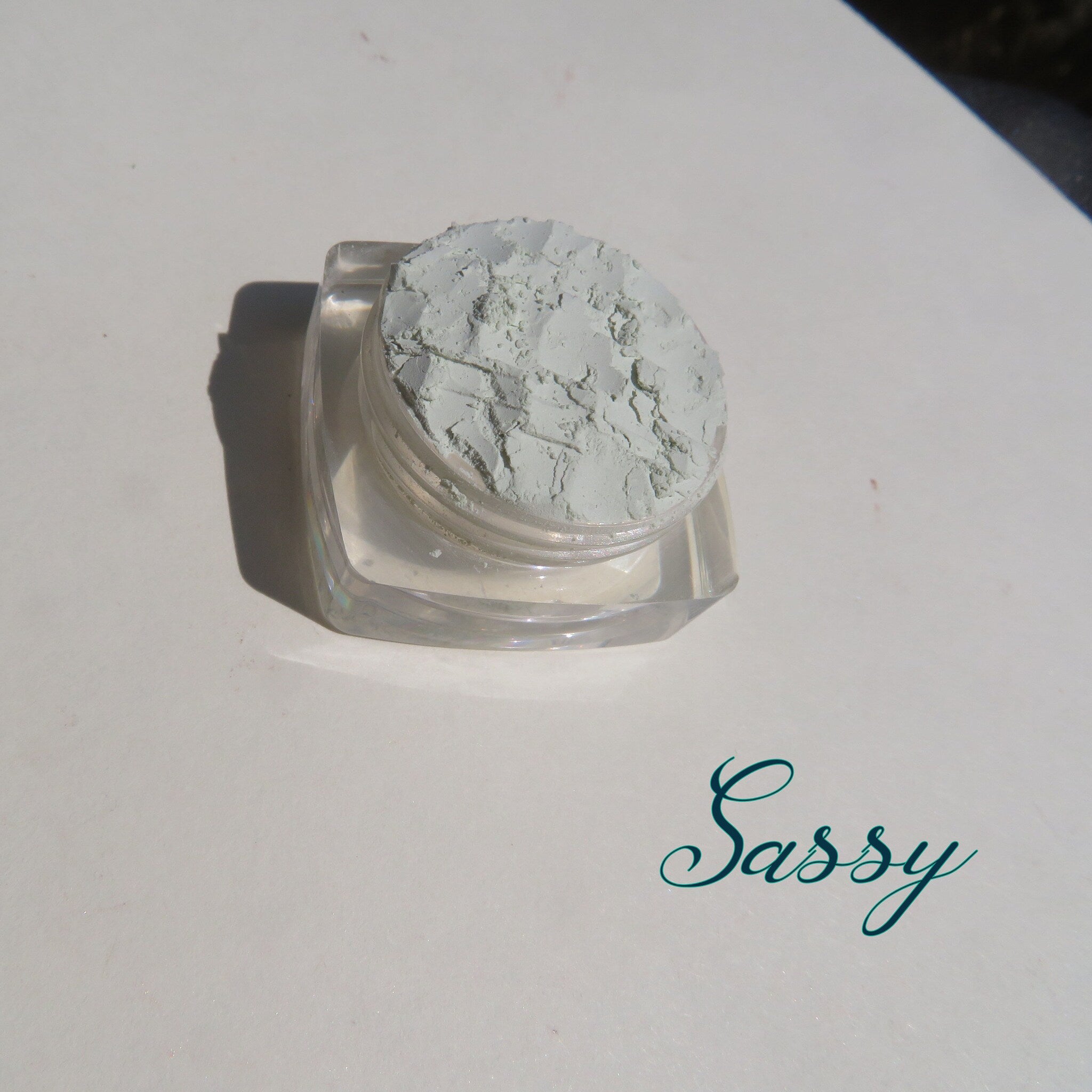 Pale green matte loose mineral eyeshadow in a clear jar with black screw-top lid, vegan and cruelty-free.