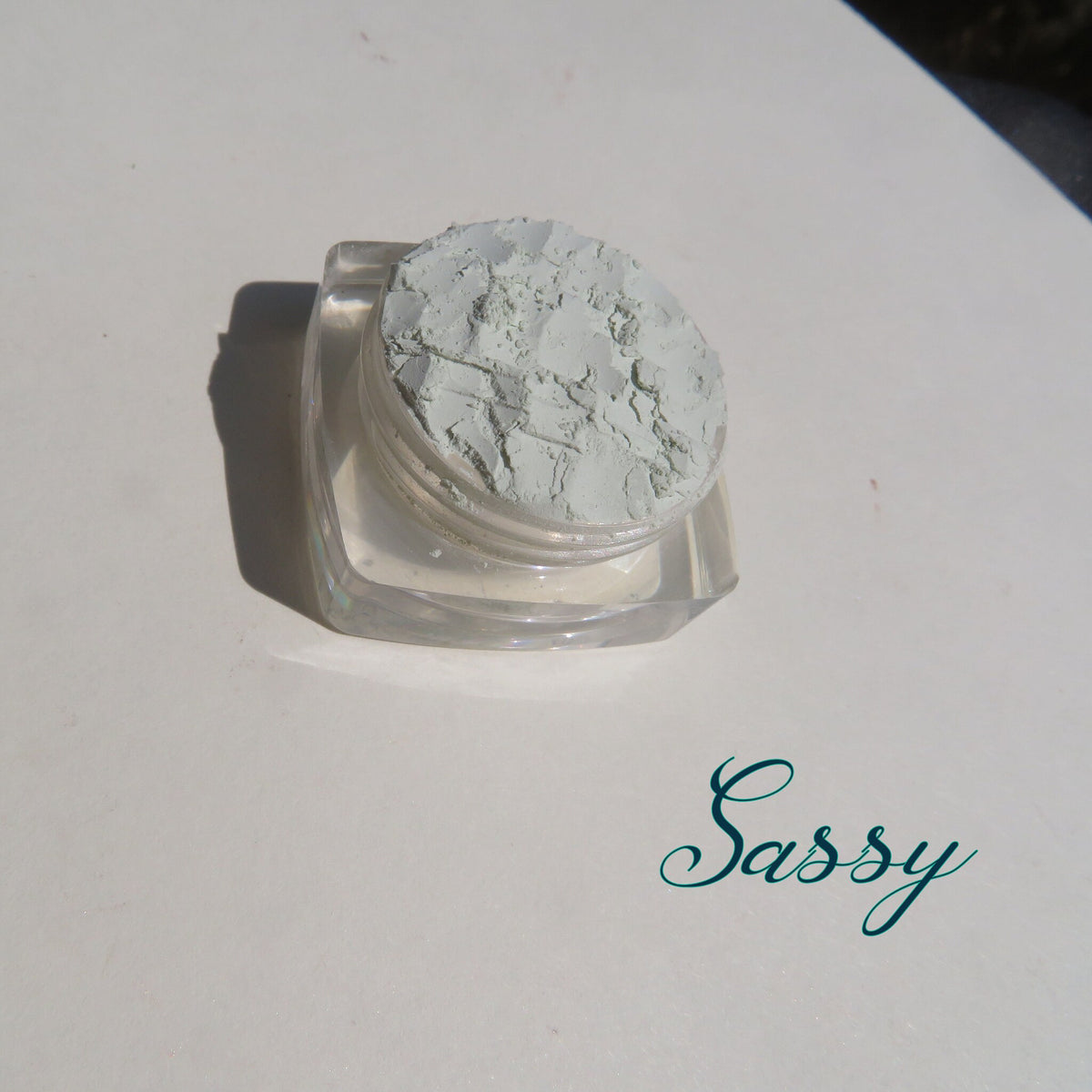 Pale green matte loose mineral eyeshadow in a clear jar with black screw-top lid, vegan and cruelty-free.