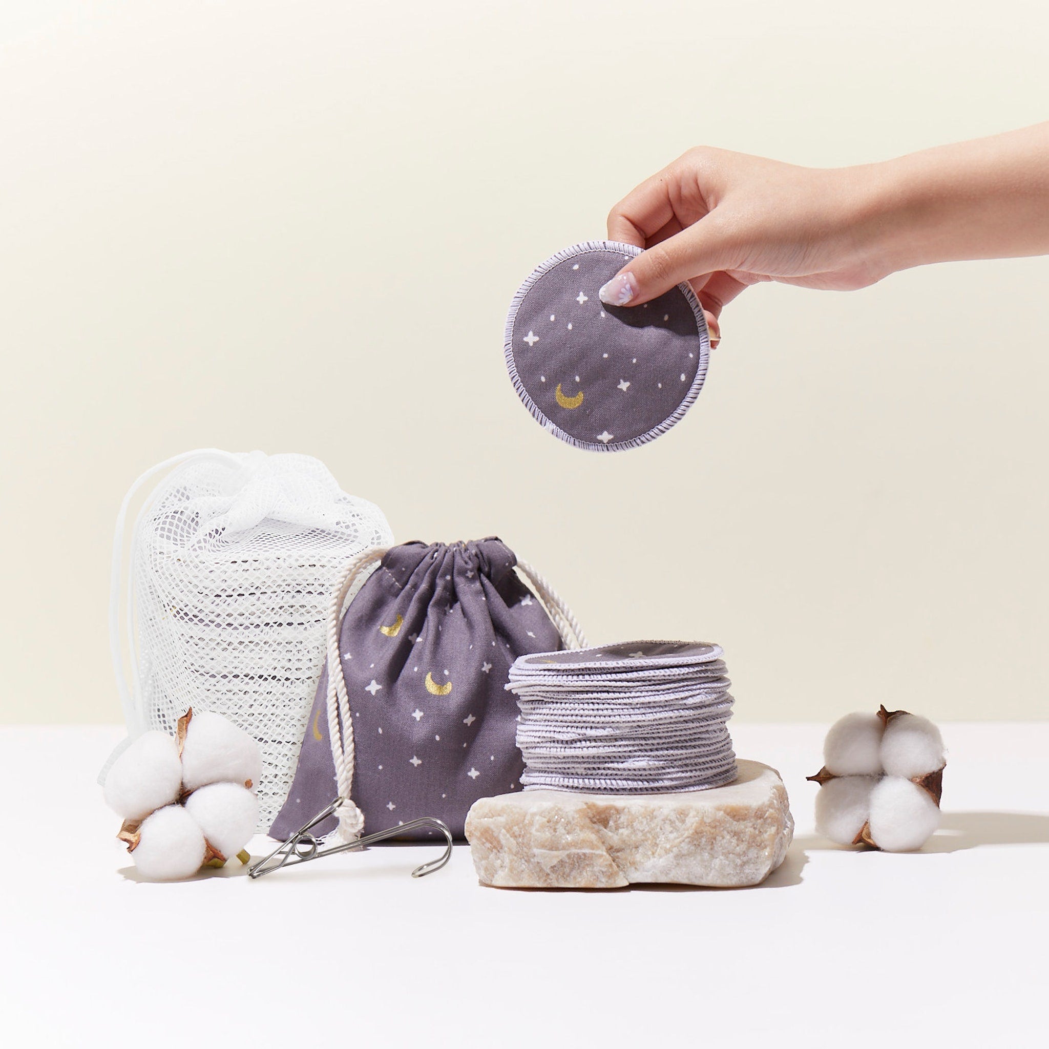 Reusable makeup remover pads, gray fabric with moon and star pattern, hand holding one pad