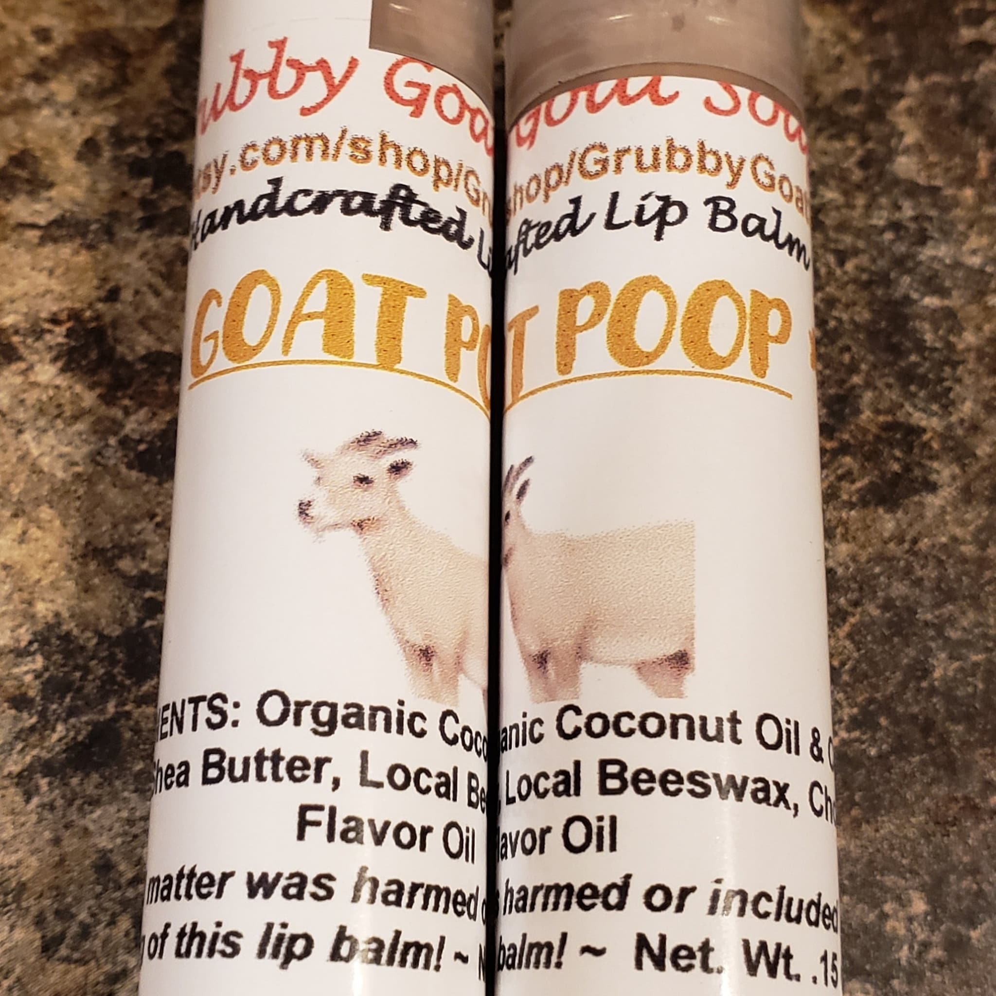 Lip balm tubes with white labels, goat illustration, and Grubby Goat text on brown background