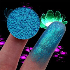 Close-up of fingertips applying duochrome shifting eye shadow in violet-blue hue with metallic sheen