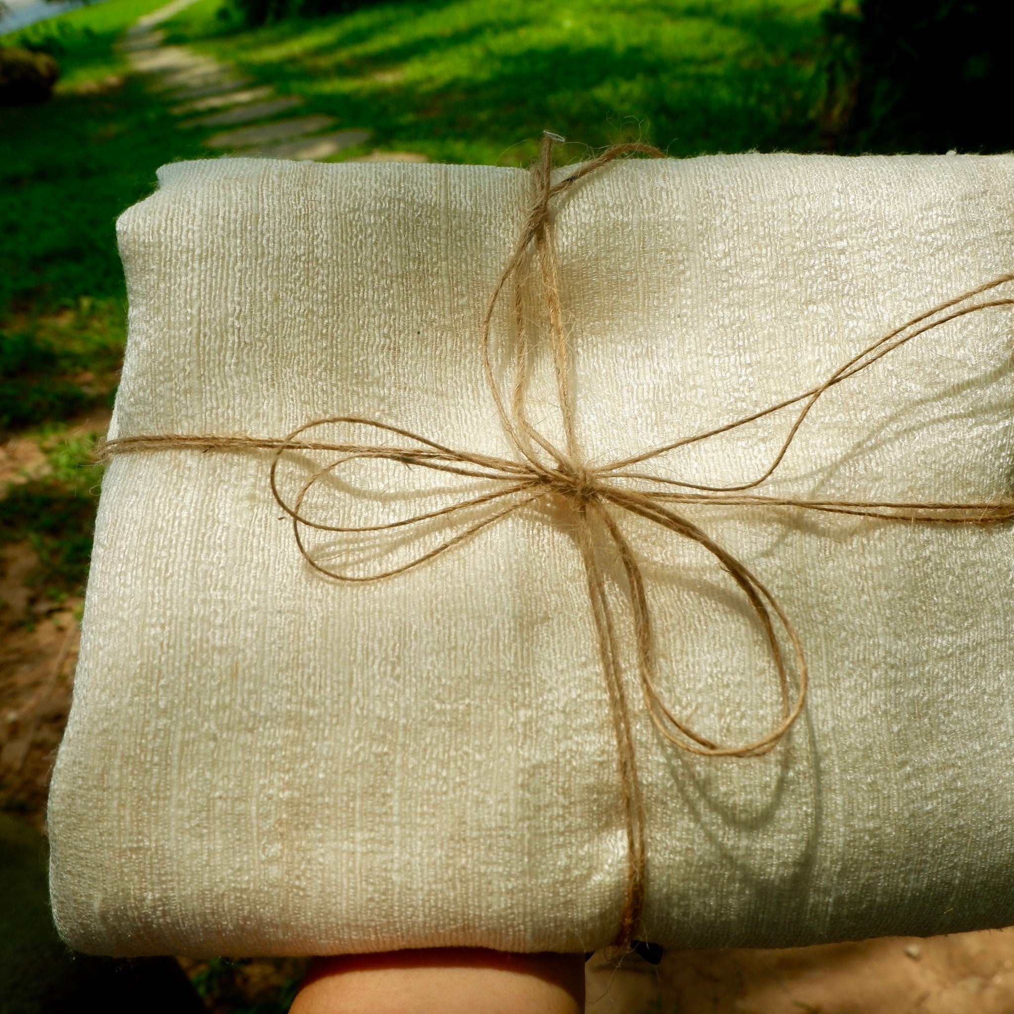 Cream fabric wrapped and tied with twine, showing woven texture and natural fibers