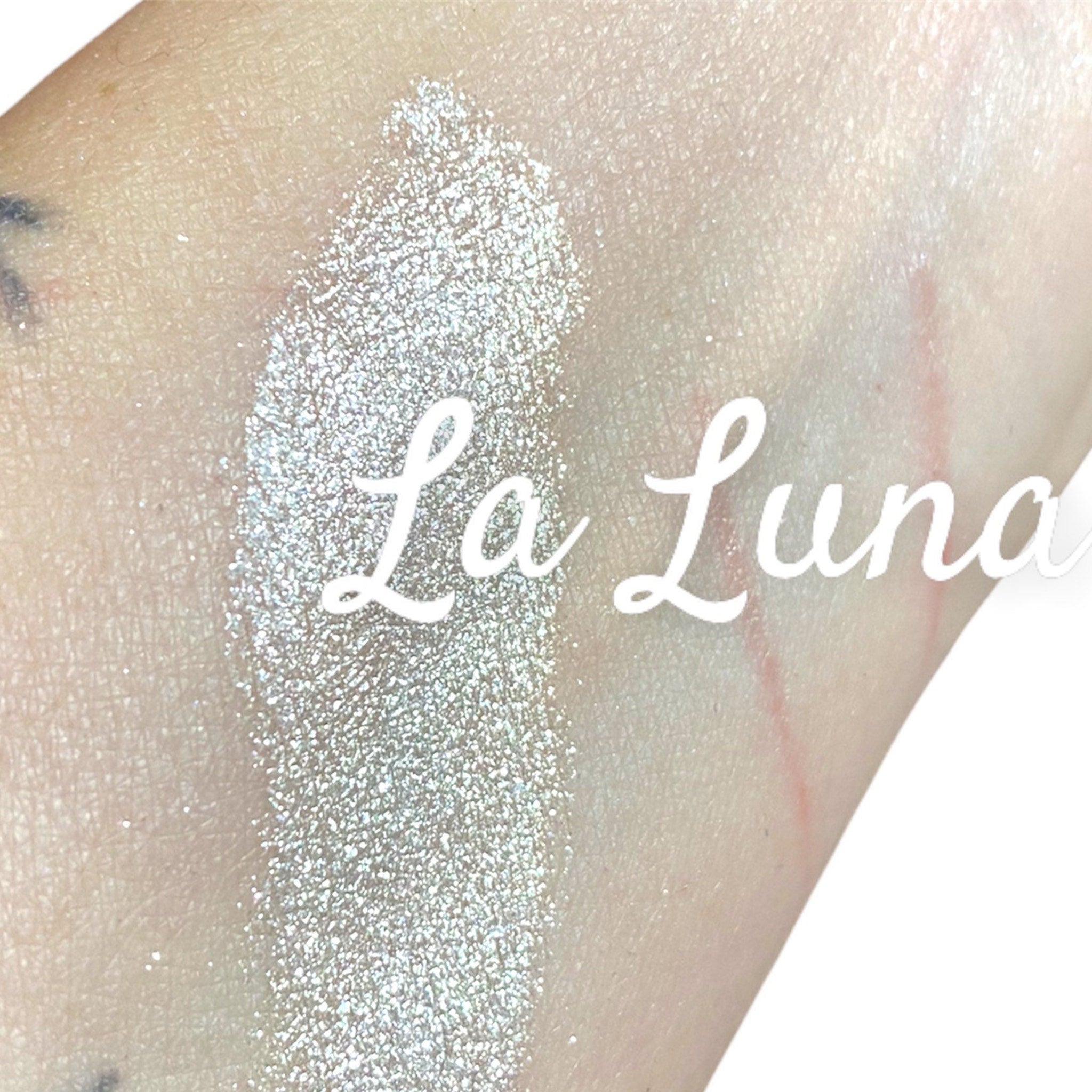Side view of LA LUNA iridescent white eyeshadow pot showing silvery glitter texture and reflective finish