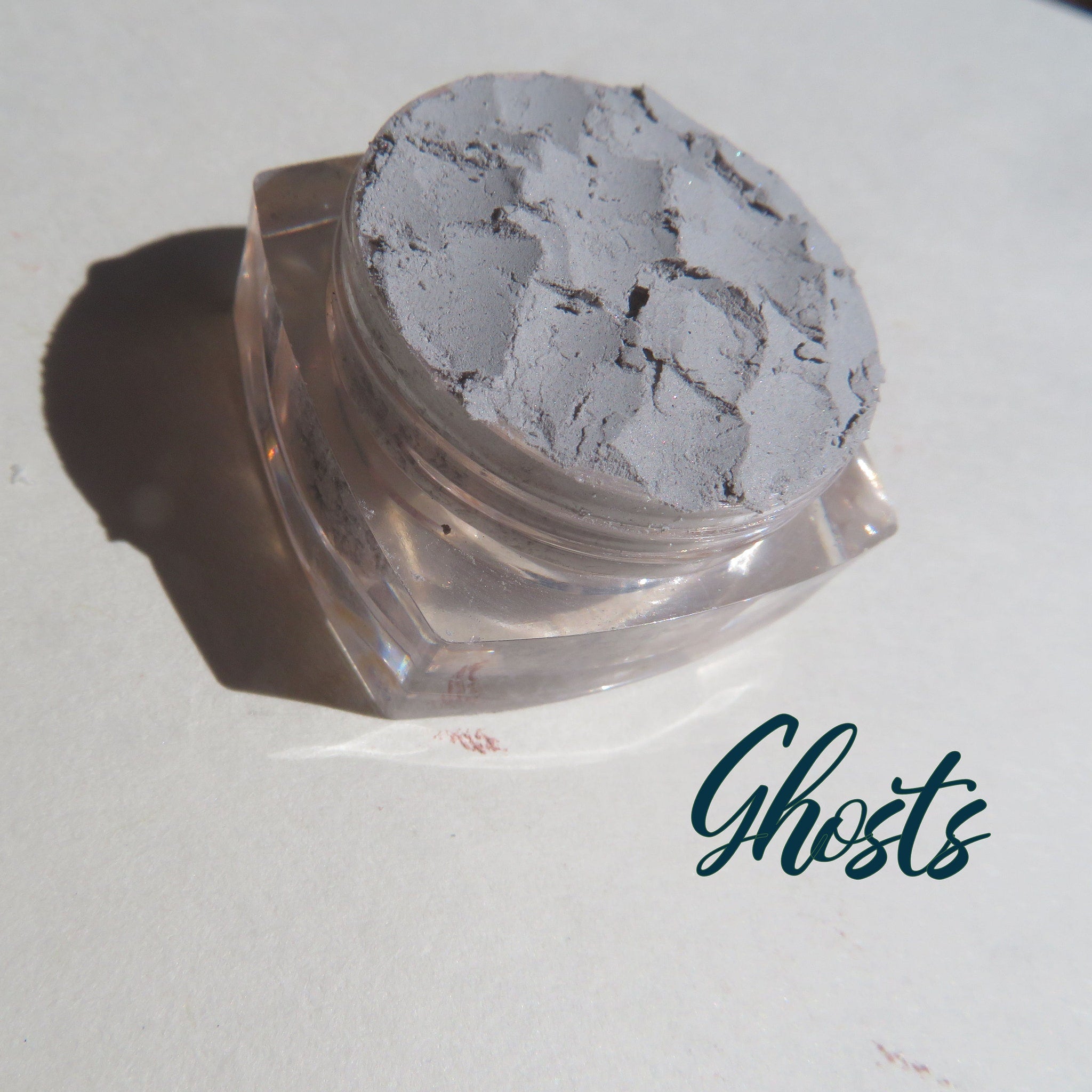Side view of pale matte gray mineral eyeshadow in eco-friendly loose powder form, showing texture and pigment density