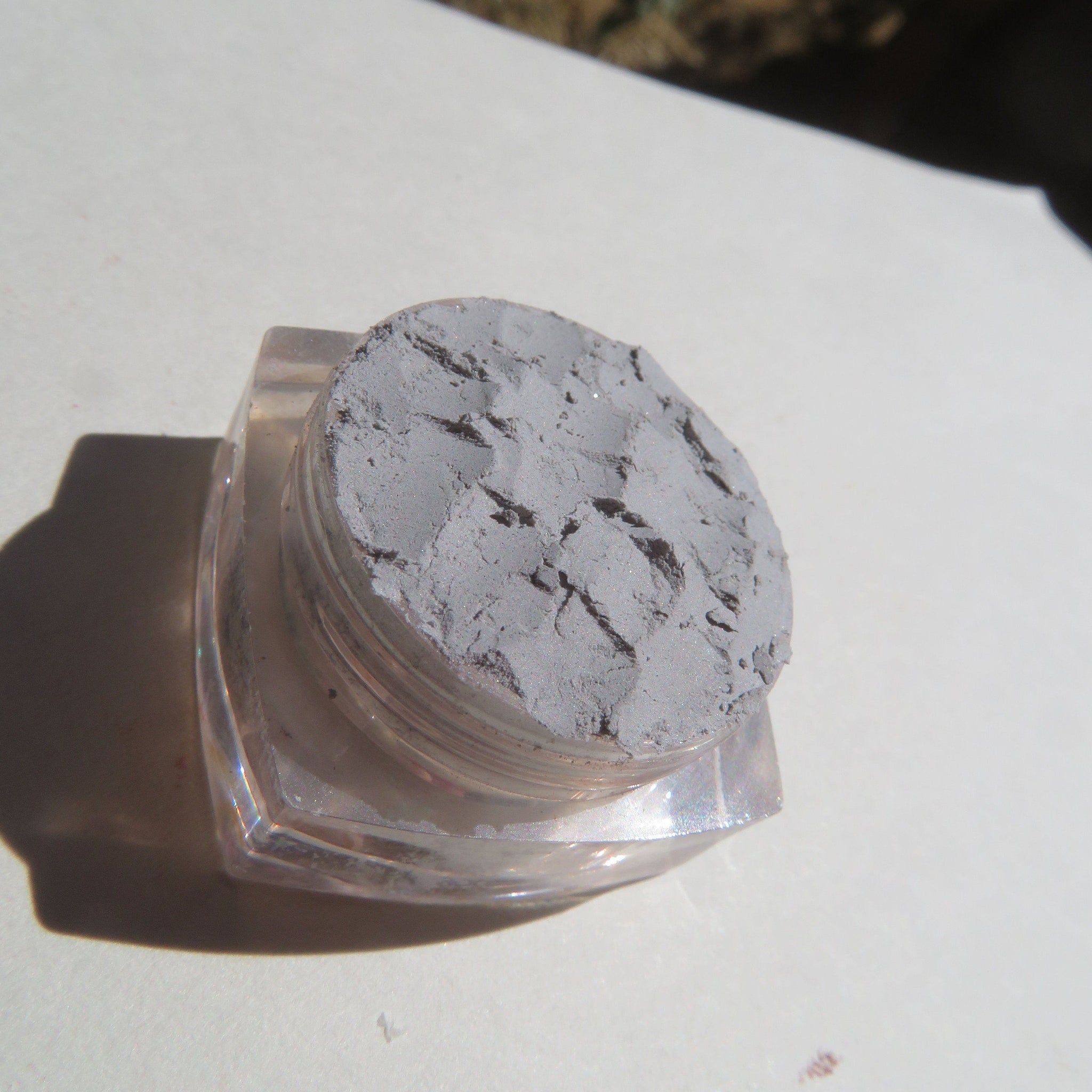 Close-up of loose pale matte gray mineral eyeshadow powder in eco-friendly packaging with vegan label