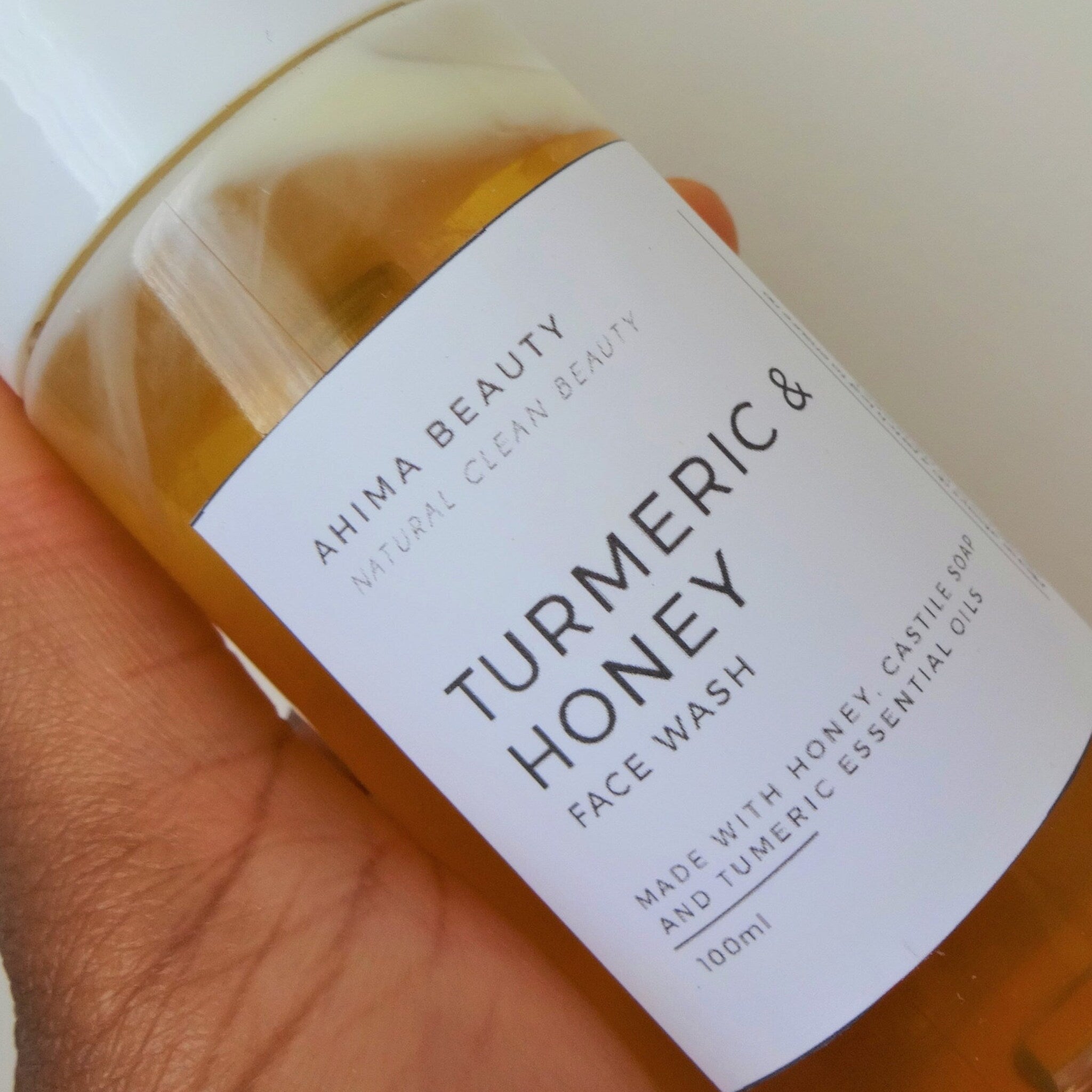 Facial Cleanser bottle with yellow liquid, white label, and brand Ahimabeauty visible in hand