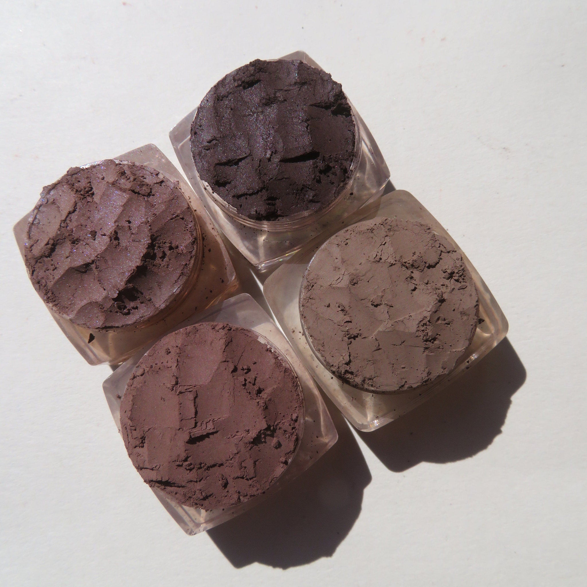 Close-up of matte brown loose mineral eyeshadows in four earthy shades with vegan labeling