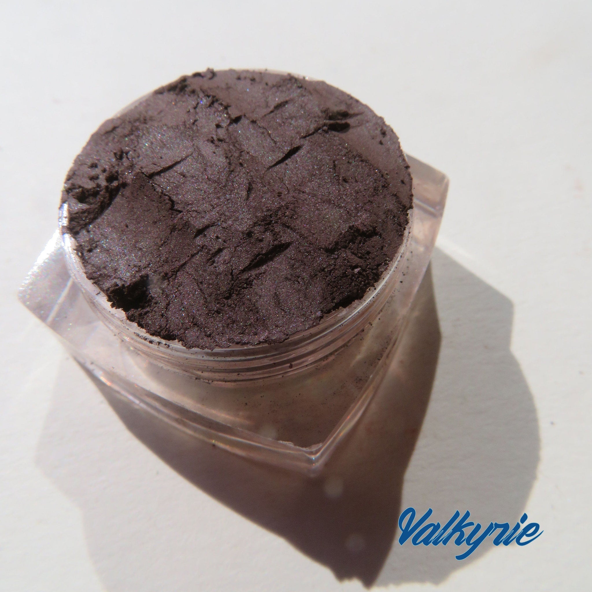 Four matte brown loose mineral eyeshadows in round jars with black lids, arranged on a white surface.