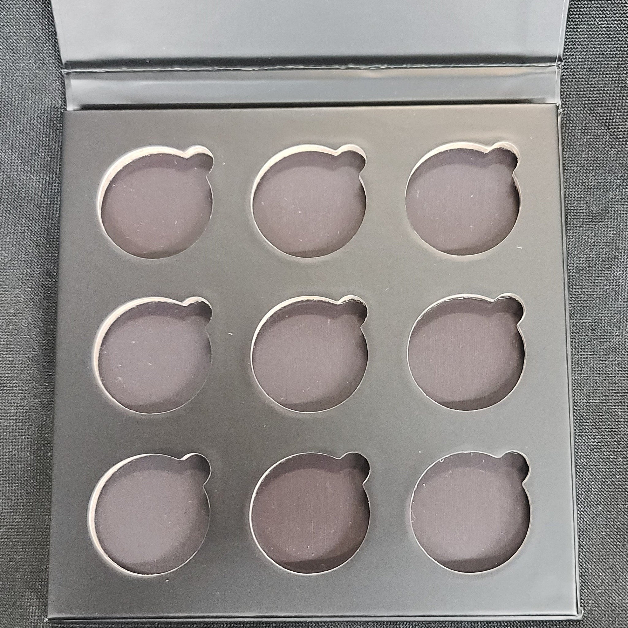Matte black rectangular eyeshadow palette with nine square pans in neutral shades, magnetic closure