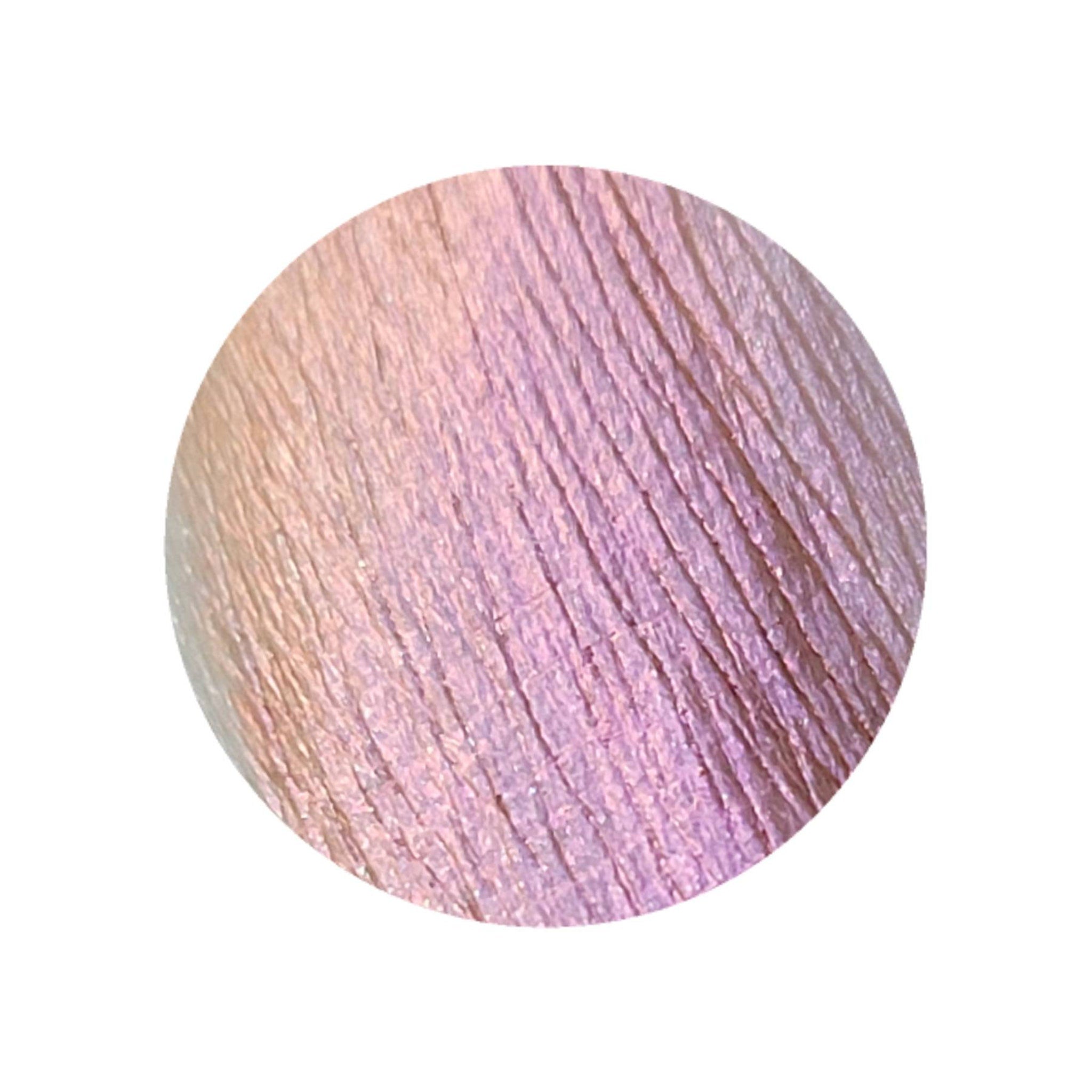 Extreme close-up of shimmery multichrome pressed eyeshadow shifting from dark orange to vibrant pink
