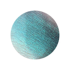 Close-up of HEKATE multichrome eyeshadow pan showing emerald green shifting to gold sparkle with metallic finish