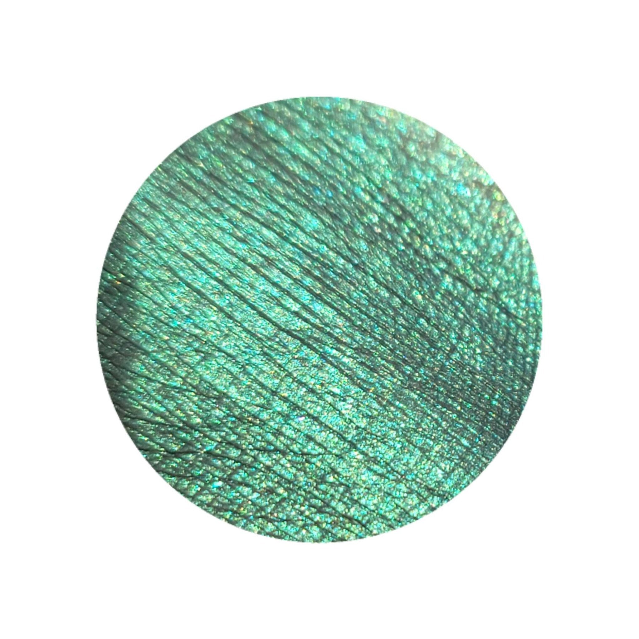 Side view of HEKATE multichrome eyeshadow pot showing emerald green and gold shimmer shift in angled light