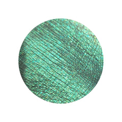Side view of HEKATE multichrome eyeshadow pot showing emerald green and gold shimmer shift in angled light