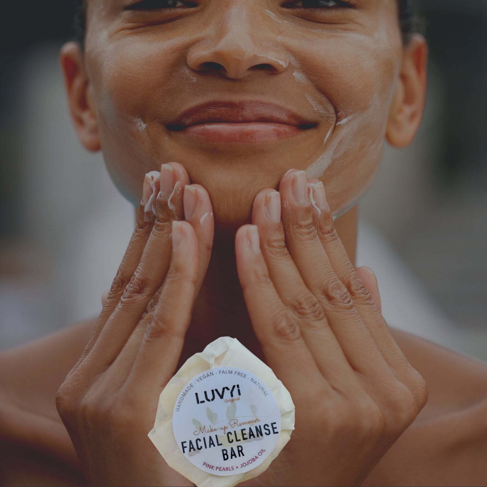 Facial cleanse bar with white foam, woman applying to face, LUVYI brand visible, round shape, white color