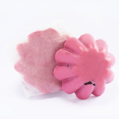 Pink flower-shaped soap with a smooth texture and a wrapped, pink, textured soap next to it.