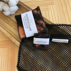 Reusable toner pads with black and brown tie-dye pattern, black trim, and mesh bag, by DBCDesignedByClaire