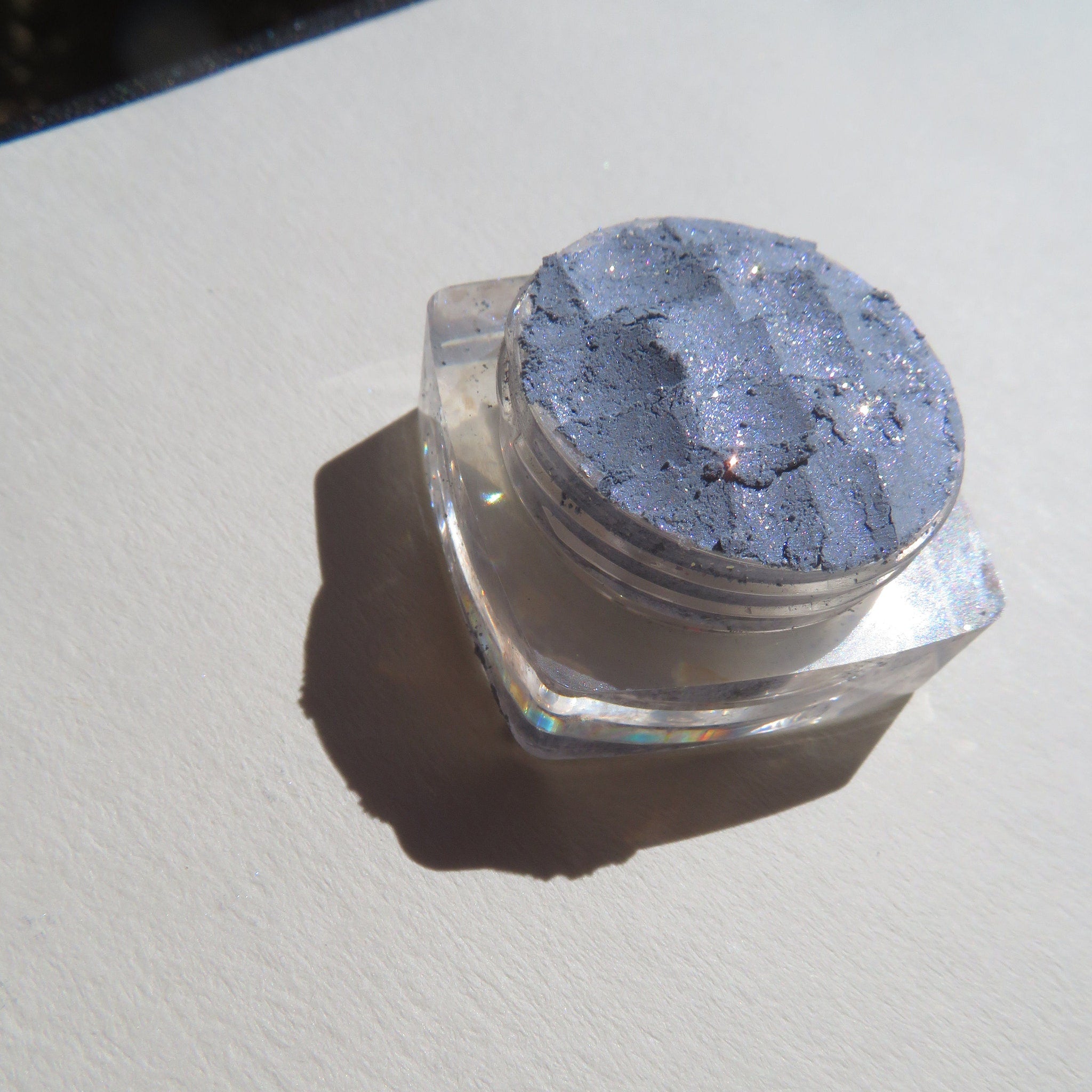 Close-up of Galactic Blue Gray loose mineral eyeshadow with intense sparkle and shimmer particles.