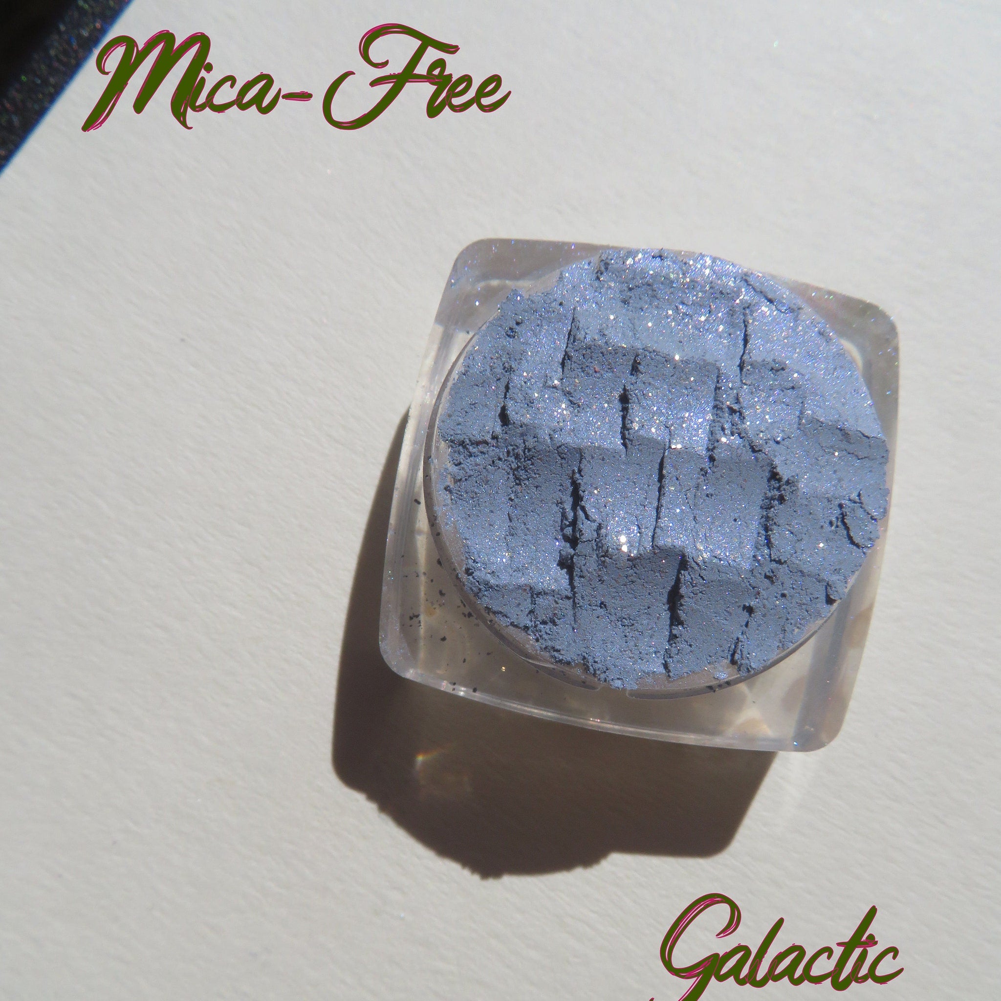 Side view of Galactic Blue Gray loose mineral eyeshadow showing sparkly shimmer texture in jar