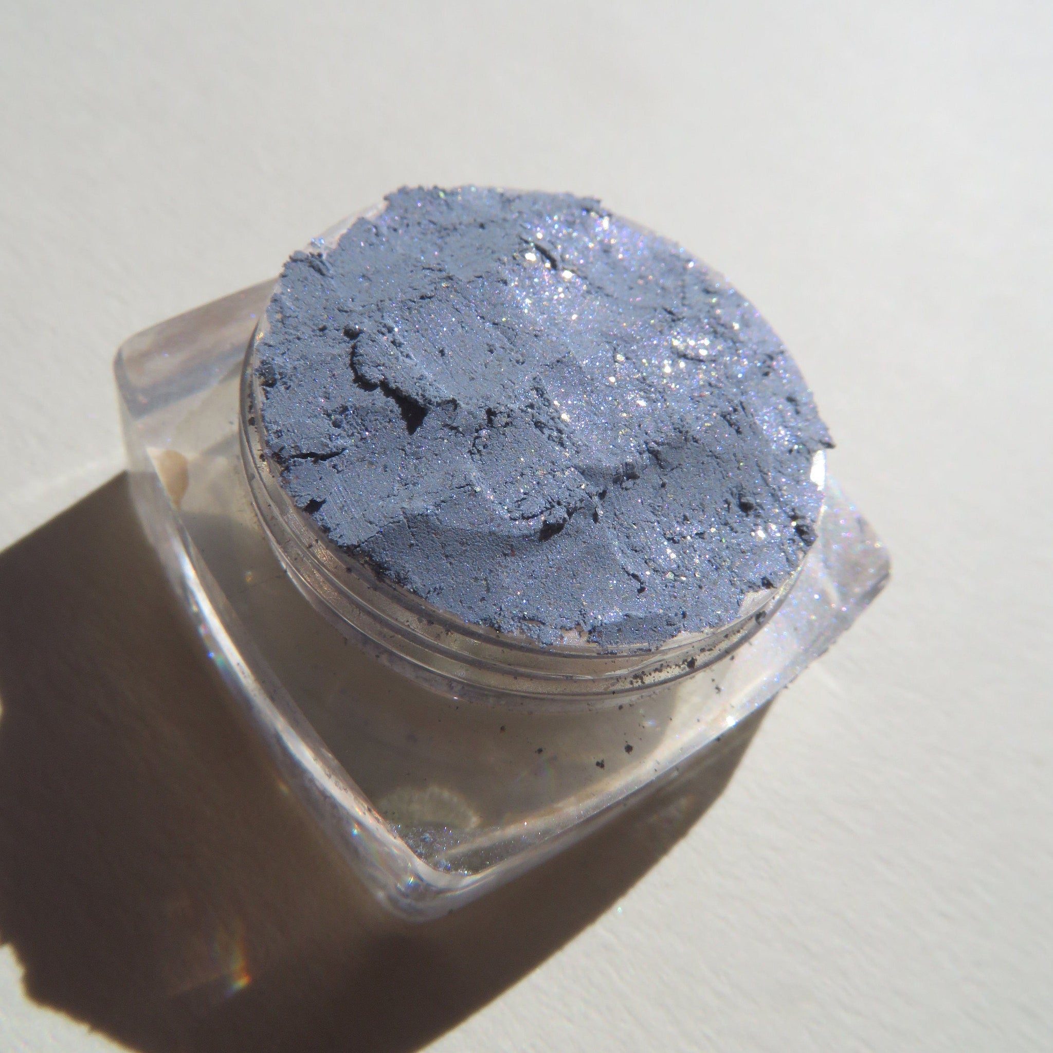 Side view of Galactic Blue Gray loose mineral eyeshadow with sparkling shimmer in a round jar