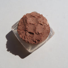 Close-up of loose mineral eyeshadow in bronze copper brown with shimmer particles catching light