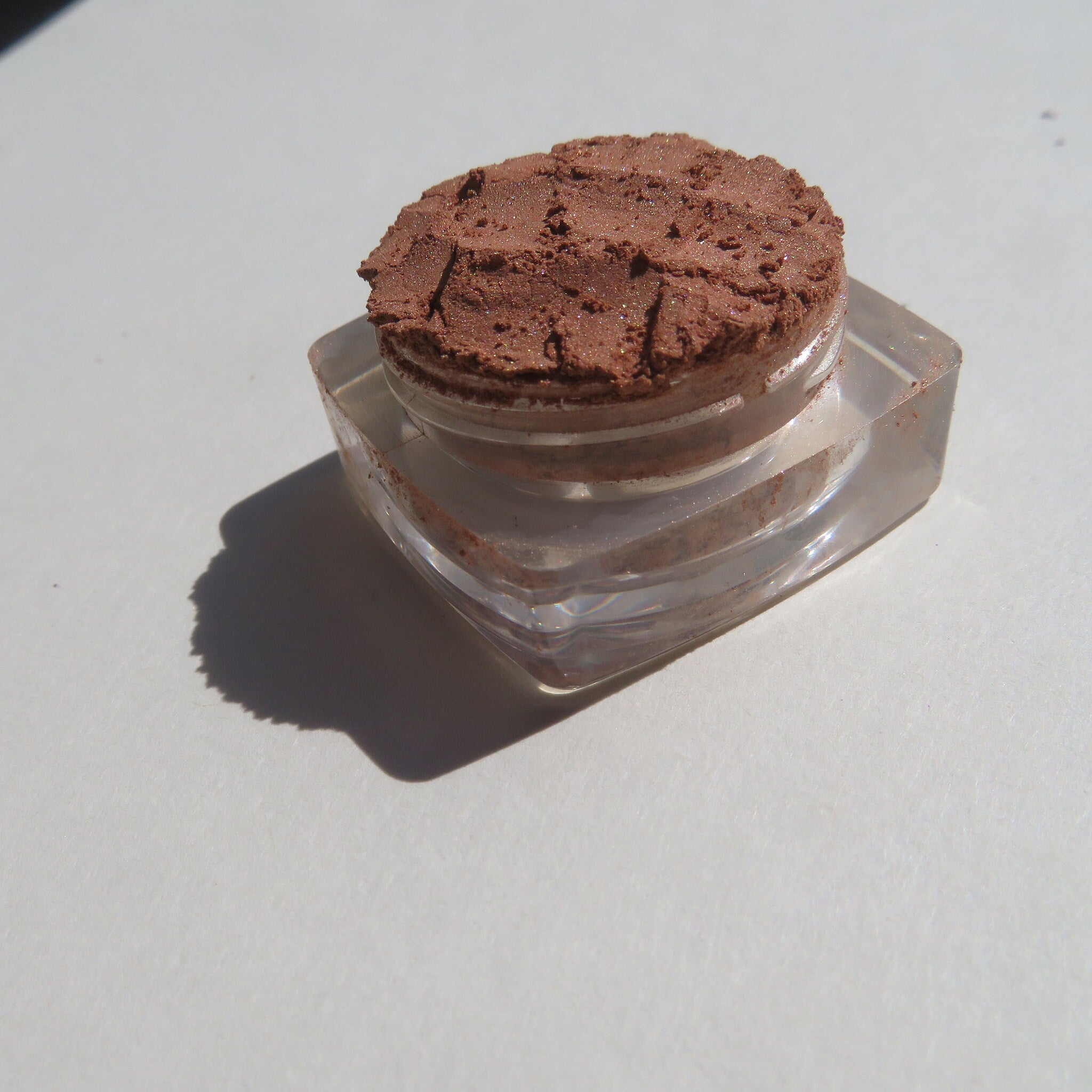 Hand applying bronze copper brown shimmer loose mineral eyeshadow with a fluffy brush for a soft, blended look