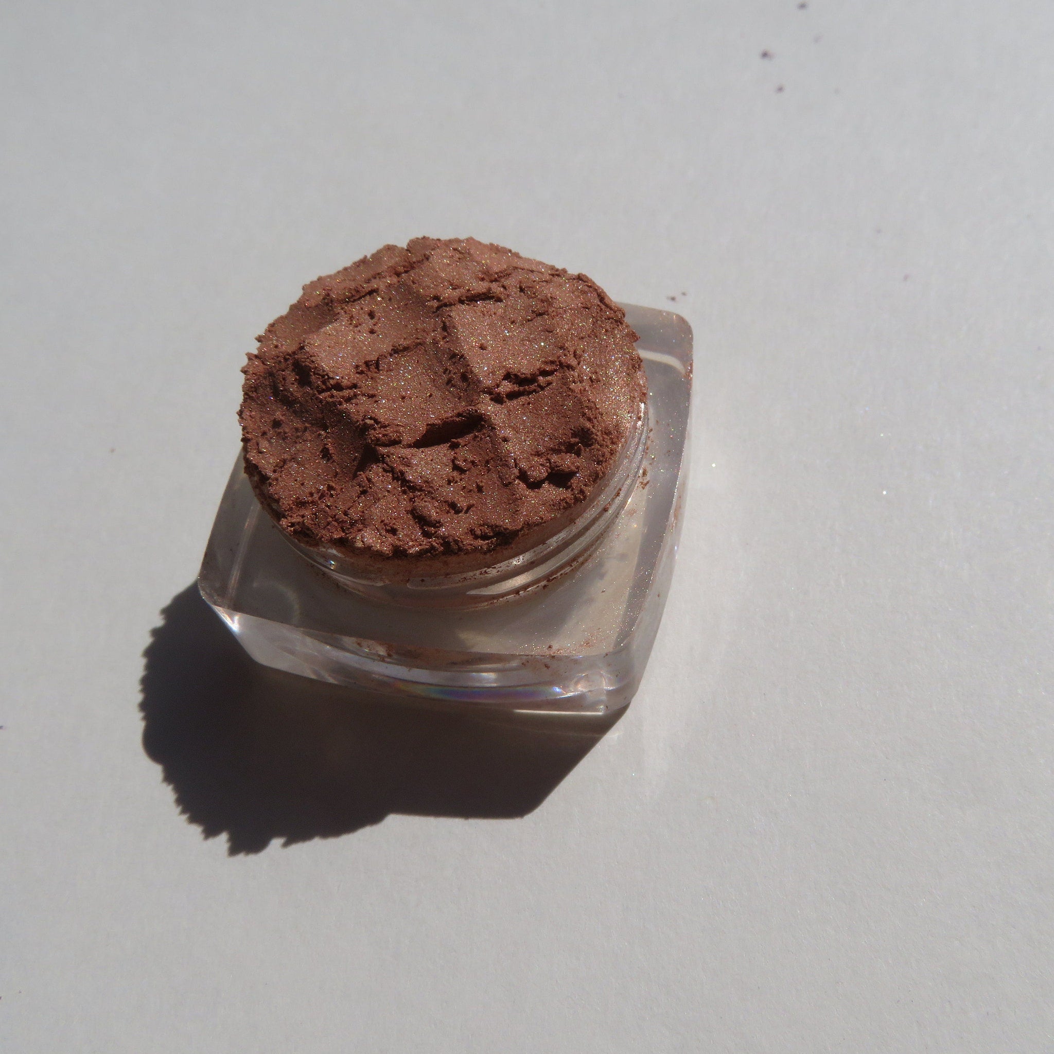Side view of bronze copper brown shimmer loose mineral eyeshadow with metallic sheen in glass jar