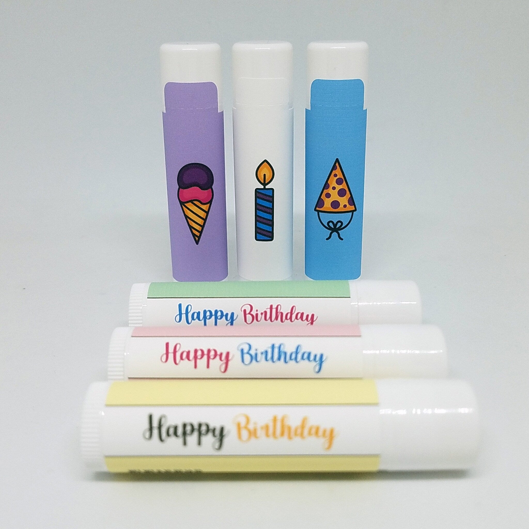 Lip balm tubes with Happy Birthday text, colorful wrappers and illustrations of ice cream, candle, and party hat