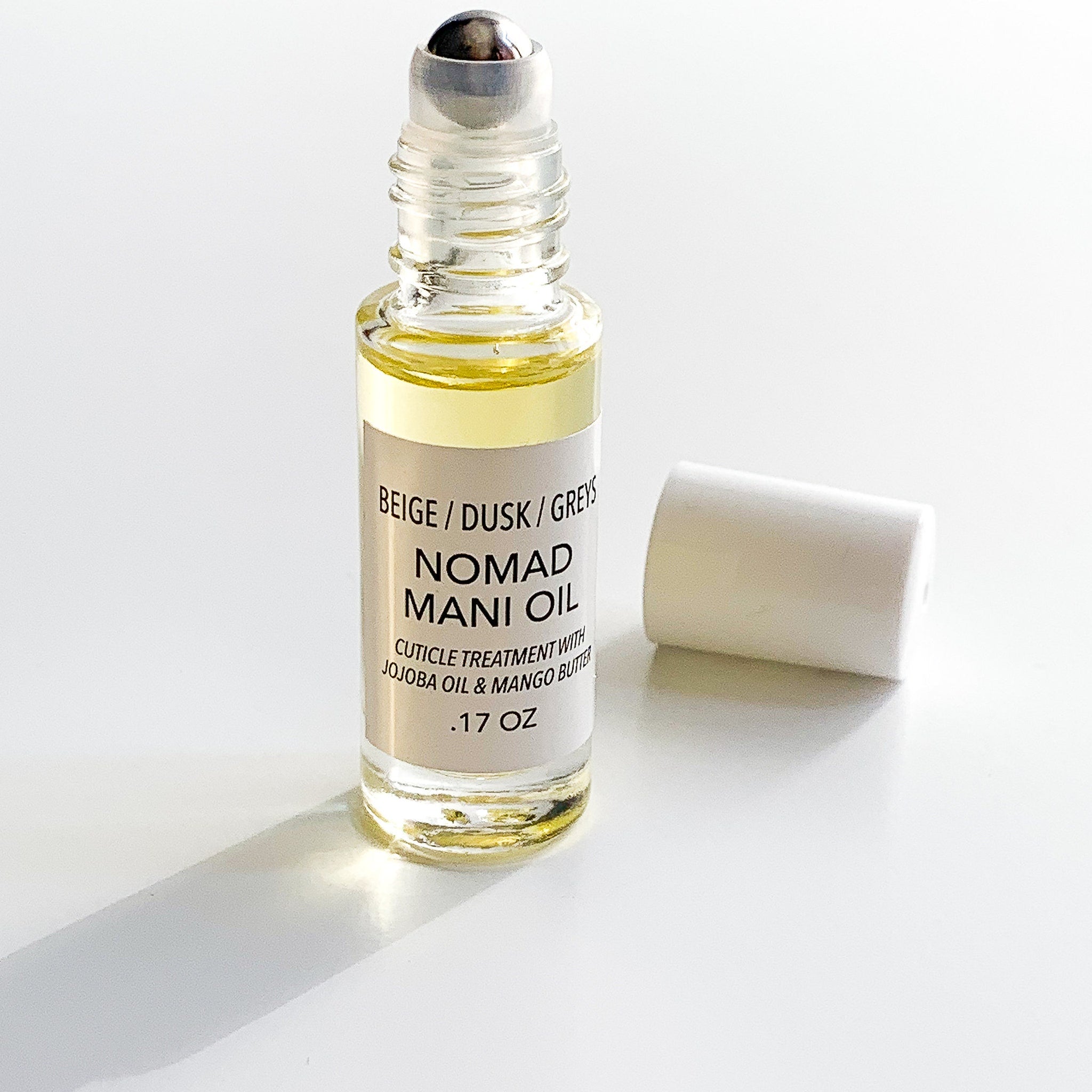 Mani oil bottle with clear glass, yellow liquid, and white label with text