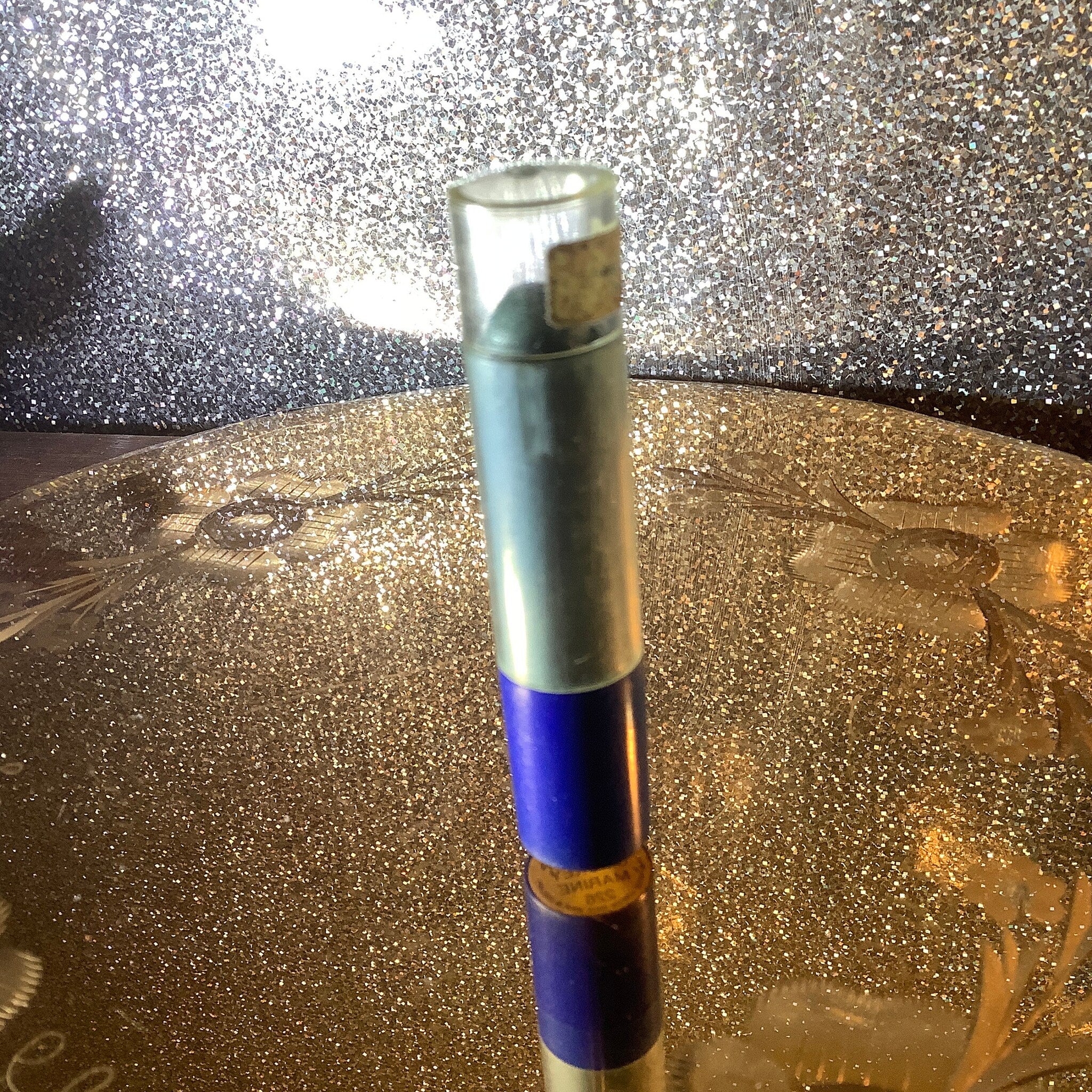 Pen with silver and blue sections, clear top, and gold label with text visible