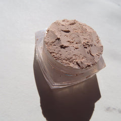 Side view of loose mineral eyeshadow in pale beige with sandy brown shimmer, showcasing eco-friendly vegan pigments