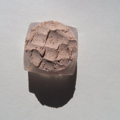 Hand applying shimmering pale beige loose mineral eyeshadow with eco-friendly brush for a sandy brown glow