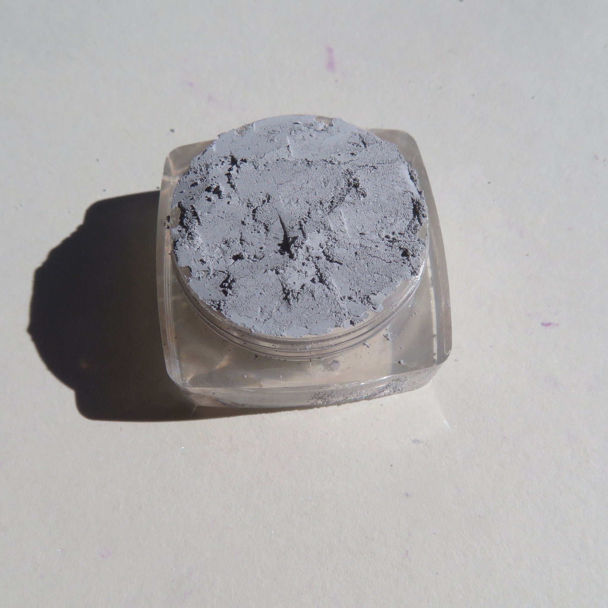 Hand applying matte gray loose pigment eyeshadow with a brush for a smoky eye look