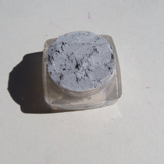 Hand applying matte gray loose pigment eyeshadow with a brush for a smoky eye look